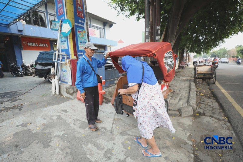 Seorang tukang becak mengantar seorang penumpang menggunakan becak listrik di Pasar Depok Jaya, Jawa Barat, Senin (12/10/2026). (CNBC Indonesia/Tri Susilo)