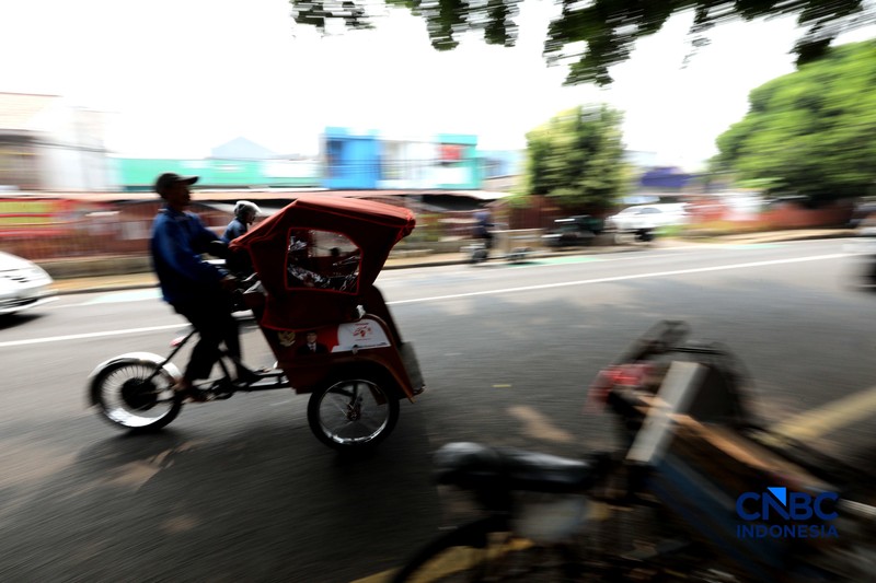 Seorang tukang becak mengantar seorang penumpang menggunakan becak listrik di Pasar Depok Jaya, Jawa Barat, Senin (12/10/2026). (CNBC Indonesia/Tri Susilo)