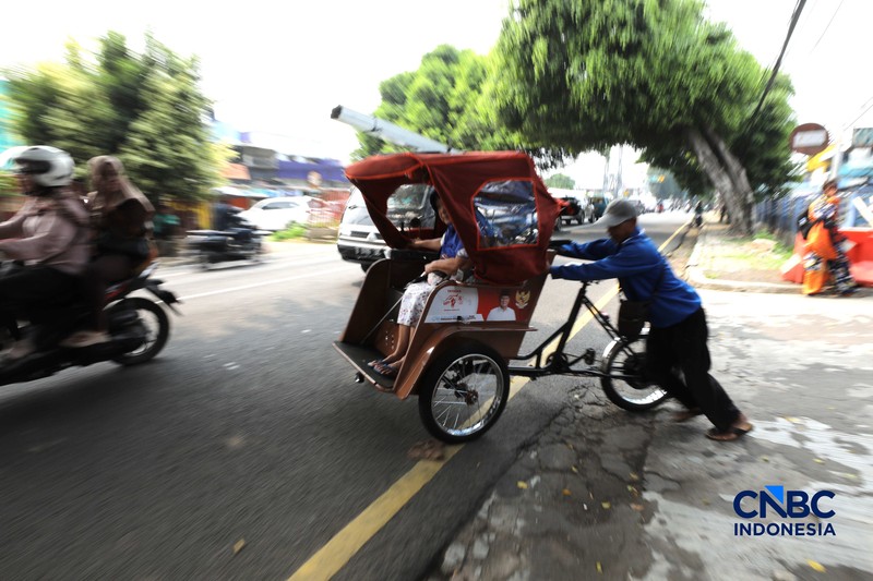 Seorang tukang becak mengantar seorang penumpang menggunakan becak listrik di Pasar Depok Jaya, Jawa Barat, Senin (12/10/2026). (CNBC Indonesia/Tri Susilo)