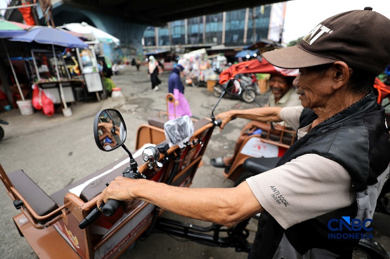 Seorang tukang becak mengantar seorang penumpang menggunakan becak listrik di Pasar Depok Jaya, Jawa Barat, Senin (12/10/2026). (CNBC Indonesia/Tri Susilo)