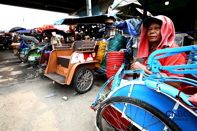 Seorang tukang becak mengantar seorang penumpang menggunakan becak listrik di Pasar Depok Jaya, Jawa Barat, Senin (12/10/2026). (CNBC Indonesia/Tri Susilo)