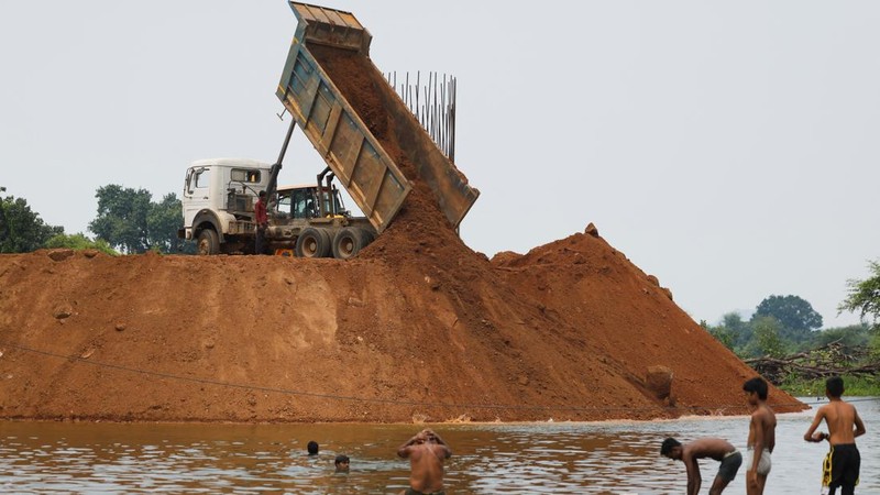 Warga desa mandi di tengah air banjir di dekat lokasi pembangunan jembatan yang menghubungkan distrik Panna dan Chhatarpur, setelah sebuah jalan terendam air di area tangkapan air Proyek Penghubung Sungai Ken-Betwa dekat Ajaygarh, Madhya Pradesh, India, pada 20 September 2026.