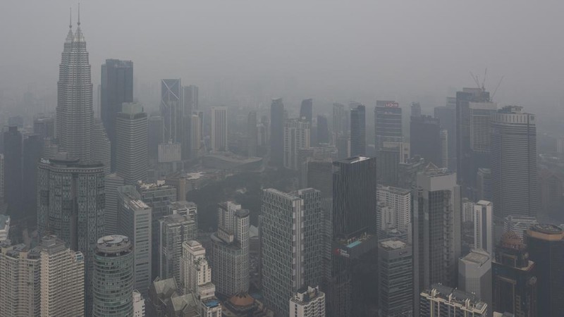 Gedung-gedung komersial terlihat diselimuti kabut di Kuala Lumpur, Malaysia, Selasa (13/10/2026). (Mohd Rasfan / AFP)