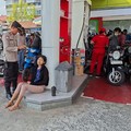 Polisi membantu mengamankan pengendara yang pingsan saat antre mengisi BBM di SPBU Latu Abiansemal, Badung, Selasa (13/10/2026). (Dok. Polsek Abiansemal via Detikcom)