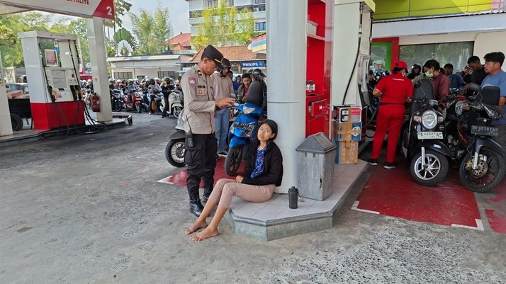 Polisi membantu mengamankan pengendara yang pingsan saat antre mengisi BBM di SPBU Latu Abiansemal, Badung, Selasa (13/10/2026). (Dok. Polsek Abiansemal via Detikcom)