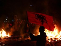 Seorang pengunjuk rasa mengibarkan bendera nasional Albania saat para mahasiswa Albania menggelar unjuk rasa anti-pemerintah di Tirana, Albania, pada 13 Oktober 2026. (REUTERS/Florion Goga)