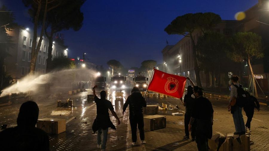 Demonstrators stand displaying a flag as water cannons are used amid an anti-government protest by students, in Tirana, Albania, October 14, 2026.