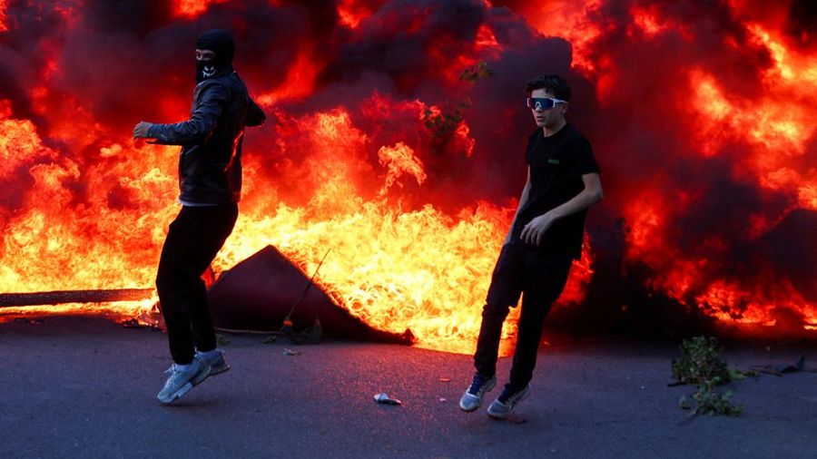 Orang-orang bereaksi di dekat kobaran api, sementara gumpalan asap hitam membubung, di tengah aksi protes anti-pemerintah oleh para mahasiswa di Tirana, Albania, 14 Oktober 2026.