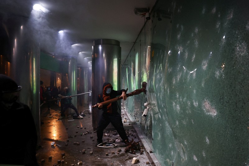 Orang-orang berkumpul di dekat api sementara gumpalan asap hitam membubung, di tengah aksi protes anti-pemerintah oleh para mahasiswa, di Tirana, Albania, 14 Oktober 2026. (REUTERS/Florion Goga)