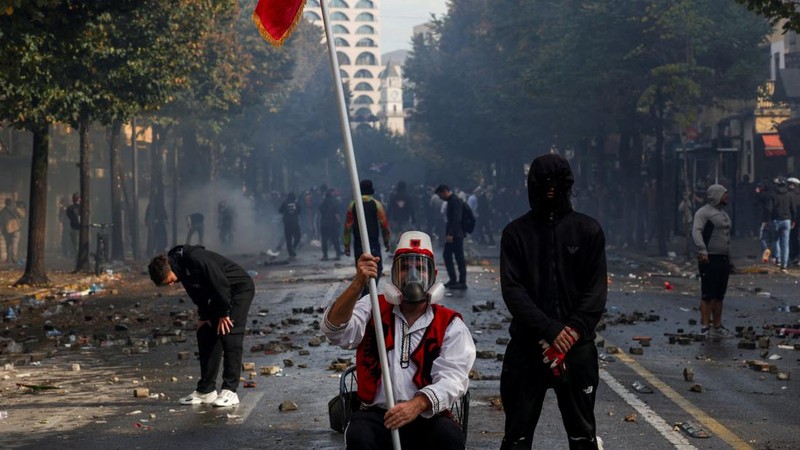 Seorang pria yang mengenakan pakaian menyerupai busana tradisional Albania duduk di tengah puing-puing yang berserakan saat berlangsungnya aksi protes anti-pemerintah oleh para mahasiswa di Tirana, Albania, pada 14 Oktober 2026.