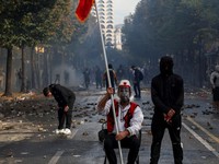 Seorang pria yang mengenakan pakaian menyerupai busana tradisional Albania duduk di tengah puing-puing yang berserakan saat berlangsungnya aksi protes anti-pemerintah oleh para mahasiswa di Tirana, Albania, pada 14 Oktober 2026. (REUTERS/Florion Goga
