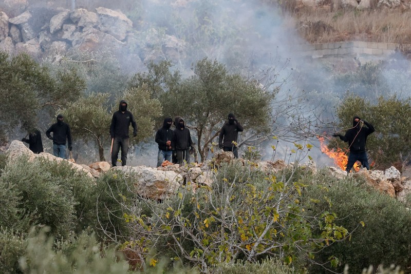 Para pemukim Israel berada di dekat api di tengah bentrokan dengan warga Palestina saat musim panen zaitun di Abu Falah, dekat Ramallah, di Tepi Barat yang diduduki Israel, 16 Oktober 2026. (REUTERS/Ammar Awad)
