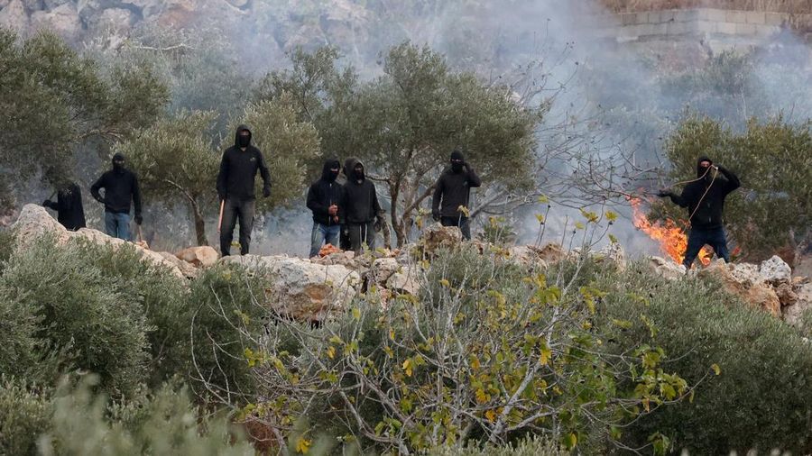 Para pemukim Israel berada di dekat api di tengah bentrokan dengan warga Palestina saat musim panen zaitun di Abu Falah, dekat Ramallah, di Tepi Barat yang diduduki Israel, 16 Oktober 2026. (REUTERS/Ammar Awad)