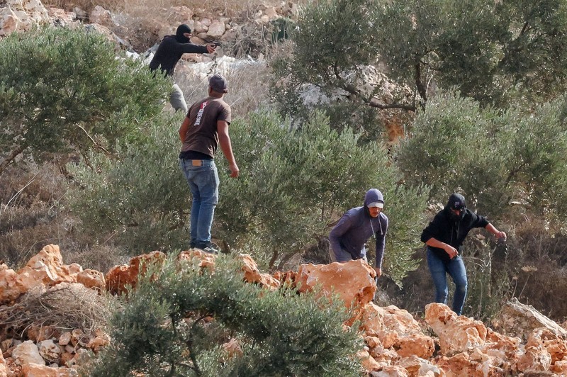 Para pemukim Israel berada di dekat api di tengah bentrokan dengan warga Palestina saat musim panen zaitun di Abu Falah, dekat Ramallah, di Tepi Barat yang diduduki Israel, 16 Oktober 2026. (REUTERS/Ammar Awad)