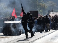 Seorang pengunjuk rasa bertopeng mengangkat lengan di tengah kepulan asap dan tempat sampah yang terguling dalam sebuah aksi protes mahasiswa yang diwarnai bentrokan dengan polisi di Roma, Italia, 16 Oktober 2026. (REUTERS/Francesco Fotia)