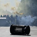 Seorang pengunjuk rasa memegang suar asap sementara para pengunjuk rasa bertopeng berkumpul di sekitar tempat sampah yang digulingkan dalam sebuah aksi protes mahasiswa di Roma, Italia, pada 16 Oktober 2026. (REUTERS/Francesco Fotia)