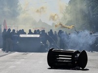Seorang pengunjuk rasa memegang suar asap sementara para pengunjuk rasa bertopeng berkumpul di sekitar tempat sampah yang digulingkan dalam sebuah aksi protes mahasiswa di Roma, Italia, pada 16 Oktober 2026. (REUTERS/Francesco Fotia)