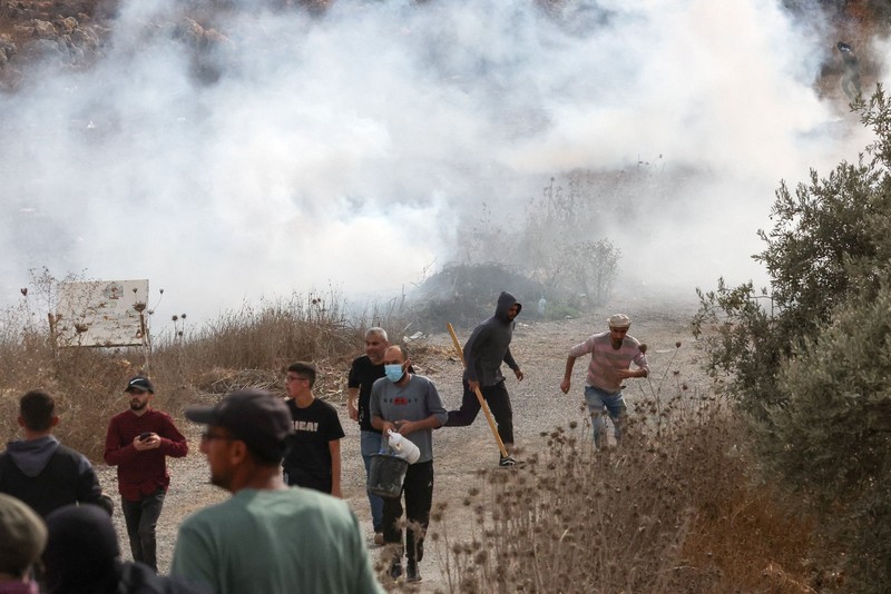 Para pemukim Israel berada di dekat api di tengah bentrokan dengan warga Palestina saat musim panen zaitun di Abu Falah, dekat Ramallah, di Tepi Barat yang diduduki Israel, 16 Oktober 2026. (REUTERS/Ammar Awad)