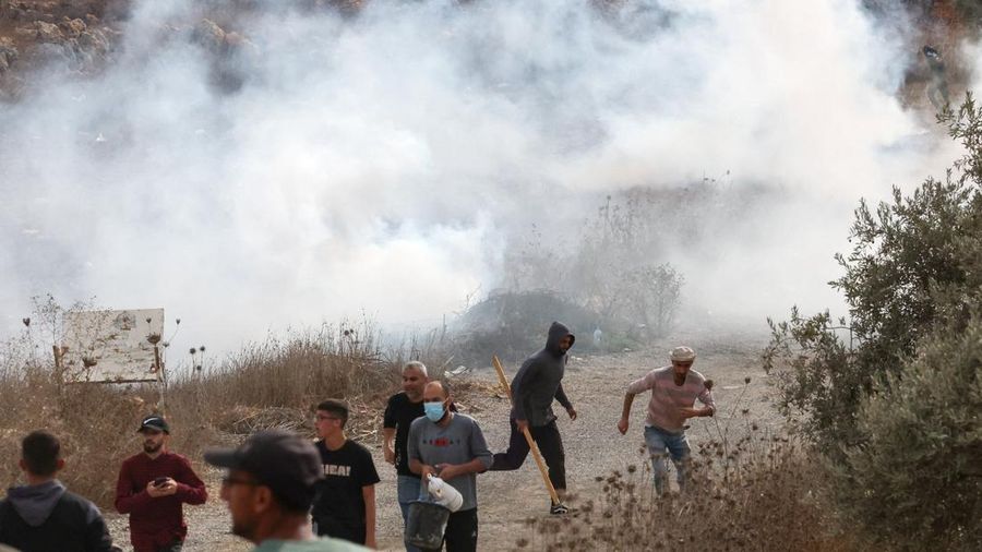 Warga Palestina berada di dekat kepulan asap di tengah bentrokan dengan para pemukim Israel saat musim panen zaitun di Abu Falah, dekat Ramallah, di Tepi Barat yang diduduki Israel, 16 Oktober 2026.