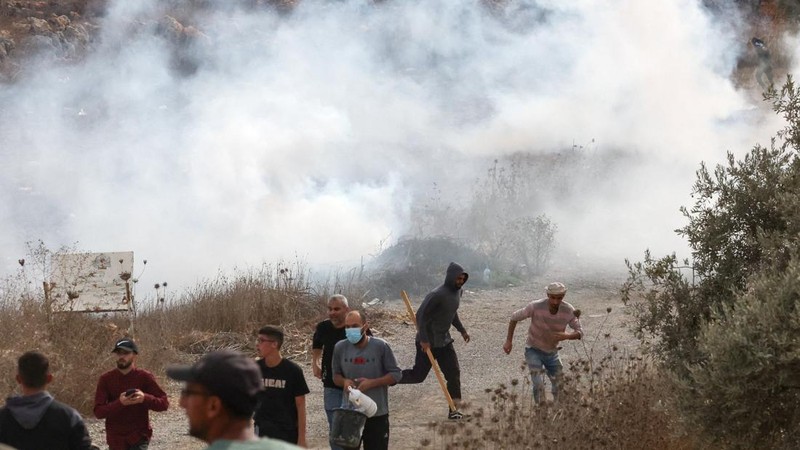 Warga Palestina berada di dekat kepulan asap di tengah bentrokan dengan para pemukim Israel saat musim panen zaitun di Abu Falah, dekat Ramallah, di Tepi Barat yang diduduki Israel, 16 Oktober 2026.