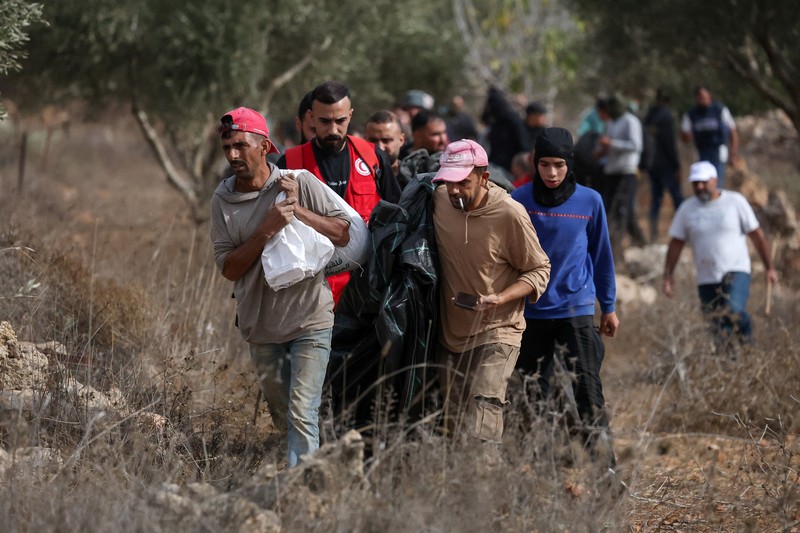 Para pemukim Israel berada di dekat api di tengah bentrokan dengan warga Palestina saat musim panen zaitun di Abu Falah, dekat Ramallah, di Tepi Barat yang diduduki Israel, 16 Oktober 2026. (REUTERS/Ammar Awad)