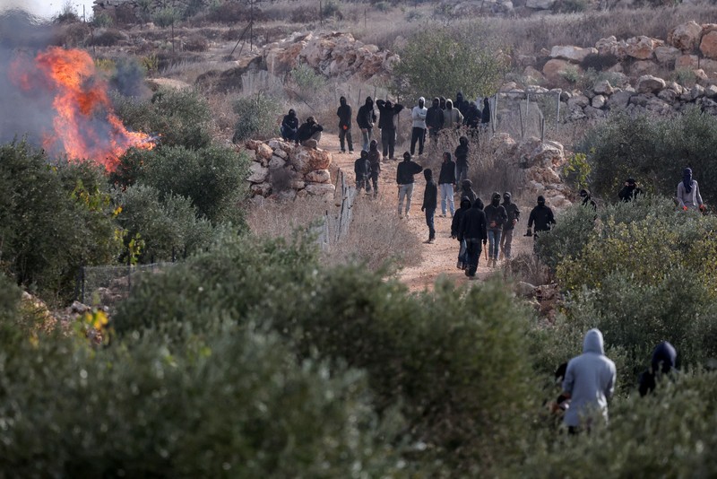 Para pemukim Israel berada di dekat api di tengah bentrokan dengan warga Palestina saat musim panen zaitun di Abu Falah, dekat Ramallah, di Tepi Barat yang diduduki Israel, 16 Oktober 2026. (REUTERS/Ammar Awad)