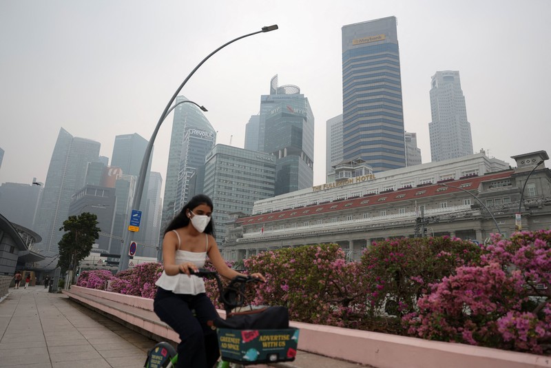 Orang-orang mengenakan masker saat kabut asap menyelimuti Singapura, Jumat (16/10/2026). (REUTERS/Edgar Su)