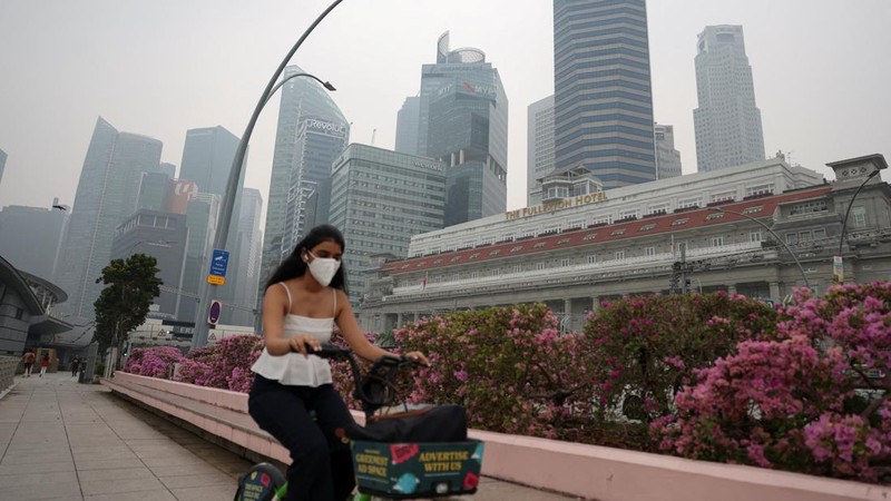 Orang-orang mengenakan masker saat kabut asap menyelimuti Singapura, Jumat (16/10/2026). (REUTERS/Edgar Su)