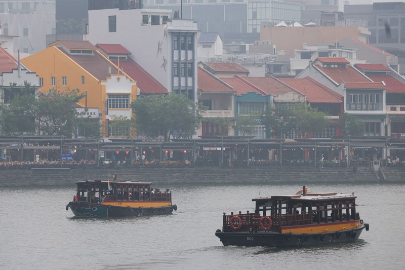 Orang-orang mengenakan masker saat kabut asap menyelimuti Singapura, Jumat (16/10/2026). (REUTERS/Edgar Su)
