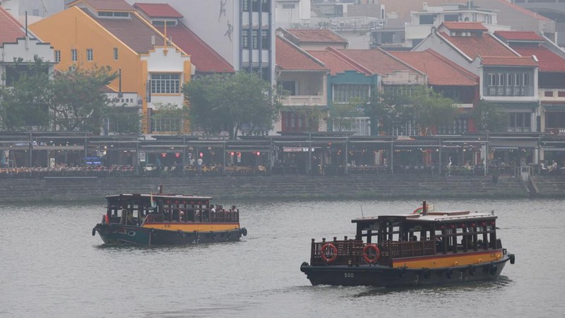 Orang-orang mengenakan masker saat kabut asap menyelimuti Singapura, Jumat (16/10/2026). (REUTERS/Edgar Su)