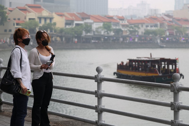 Orang-orang mengenakan masker saat kabut asap menyelimuti Singapura, Jumat (16/10/2026). (REUTERS/Edgar Su)