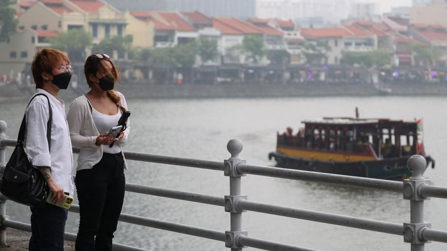 Orang-orang mengenakan masker saat kabut asap menyelimuti Singapura, Jumat (16/10/2026). (REUTERS/Edgar Su)