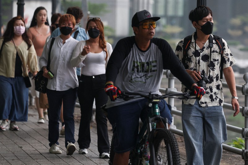 Orang-orang mengenakan masker saat kabut asap menyelimuti Singapura, Jumat (16/10/2026). (REUTERS/Edgar Su)