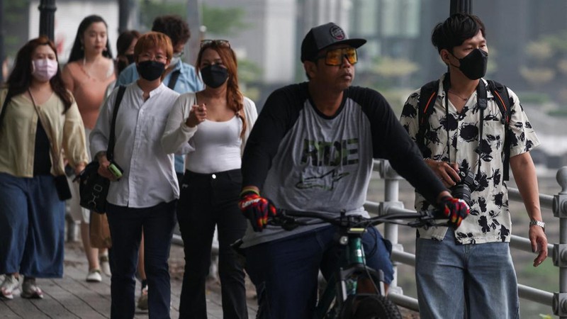 Orang-orang mengenakan masker saat kabut asap menyelimuti Singapura, Jumat (16/10/2026). (REUTERS/Edgar Su)