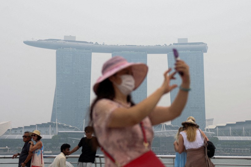 Orang-orang mengenakan masker saat kabut asap menyelimuti Singapura, Jumat (16/10/2026). (REUTERS/Edgar Su)