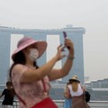 Orang-orang mengenakan masker saat kabut asap menyelimuti Singapura, Jumat (16/10/2026). (REUTERS/Edgar Su)