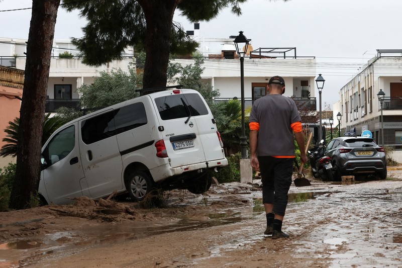 Firefighters work to remove a car on top of other objects in a mud-covered street, following torrential rains, which caused floods in eastern Spain, in Els Poblets, Alicante province, Spain, October 19, 2026. REUTERS/Eva Manez