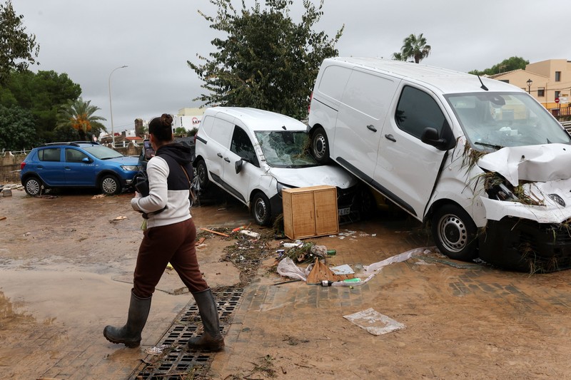 Firefighters work to remove a car on top of other objects in a mud-covered street, following torrential rains, which caused floods in eastern Spain, in Els Poblets, Alicante province, Spain, October 19, 2026. REUTERS/Eva Manez
