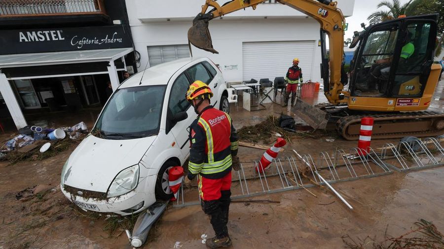 Firefighters work to remove a car on top of other objects in a mud-covered street, following torrential rains, which caused floods in eastern Spain, in Els Poblets, Alicante province, Spain, October 19, 2026. REUTERS/Eva Manez