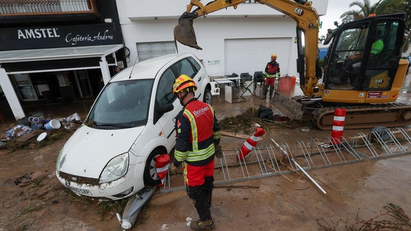 Firefighters work to remove a car on top of other objects in a mud-covered street, following torrential rains, which caused floods in eastern Spain, in Els Poblets, Alicante province, Spain, October 19, 2026. REUTERS/Eva Manez