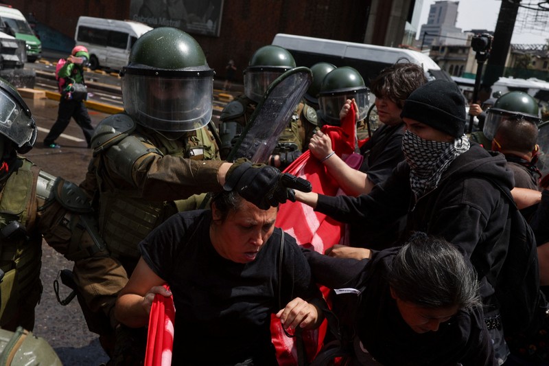 Seorang pengunjuk rasa berjalan di tengah gas air mata pada hari digelarnya aksi massa untuk memperingati tujuh tahun protes dan kerusuhan tahun 2019, di Santiago, Chili, 18 Oktober 2026. (REUTERS/Pablo Sanhueza)