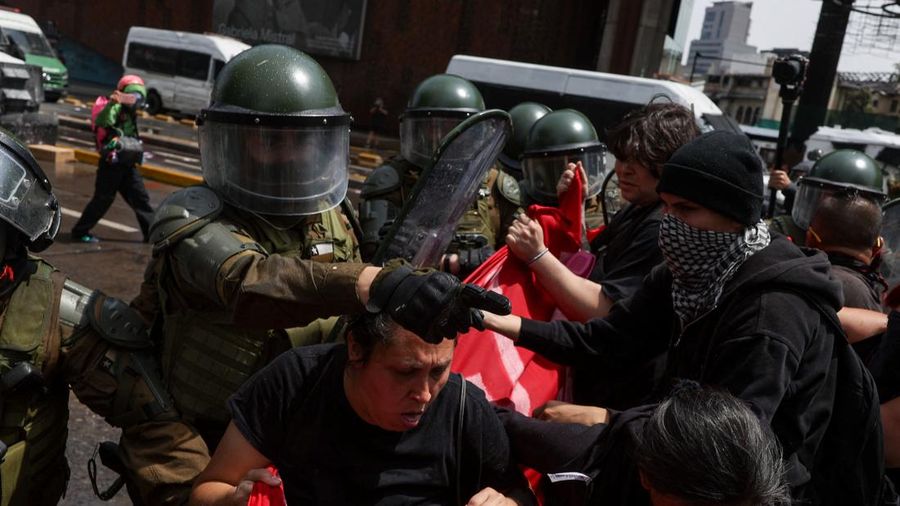 Petugas kepolisian antihuru-hara berbaris di depan para pengunjuk rasa pada hari digelarnya aksi unjuk rasa untuk menandai peringatan tujuh tahun protes dan kerusuhan tahun 2019, di Santiago, Chili, 18 Oktober 2026.