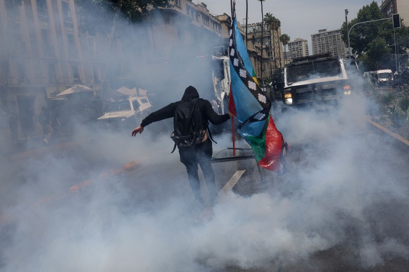 Seorang pengunjuk rasa berjalan di tengah gas air mata pada hari digelarnya aksi massa untuk memperingati tujuh tahun protes dan kerusuhan tahun 2019, di Santiago, Chili, 18 Oktober 2026. (REUTERS/Pablo Sanhueza)