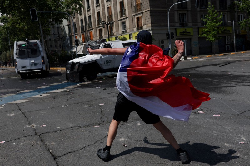 Seorang pengunjuk rasa berjalan di tengah gas air mata pada hari digelarnya aksi massa untuk memperingati tujuh tahun protes dan kerusuhan tahun 2019, di Santiago, Chili, 18 Oktober 2026. (REUTERS/Pablo Sanhueza)