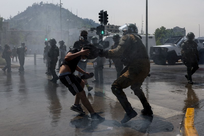 Seorang pengunjuk rasa berjalan di tengah gas air mata pada hari digelarnya aksi massa untuk memperingati tujuh tahun protes dan kerusuhan tahun 2019, di Santiago, Chili, 18 Oktober 2026. (REUTERS/Pablo Sanhueza)