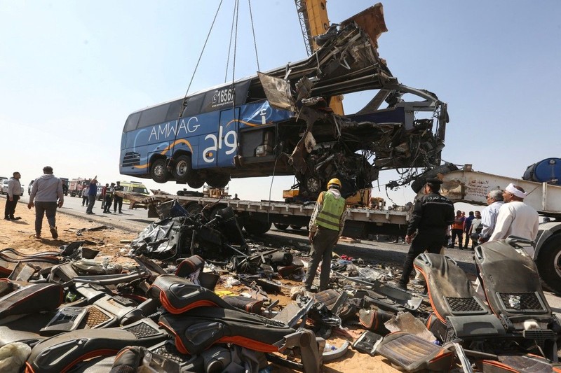 A crane lifts the wreckage of a tour bus following a crash on the desert highway in Giza on October 20, 2026. A large truck crashed into a tour bus west of the Egyptian capital on October 20, killing 13 people and injuring 34, state media reported. (Photo by Khaled KAMEL / AFP)