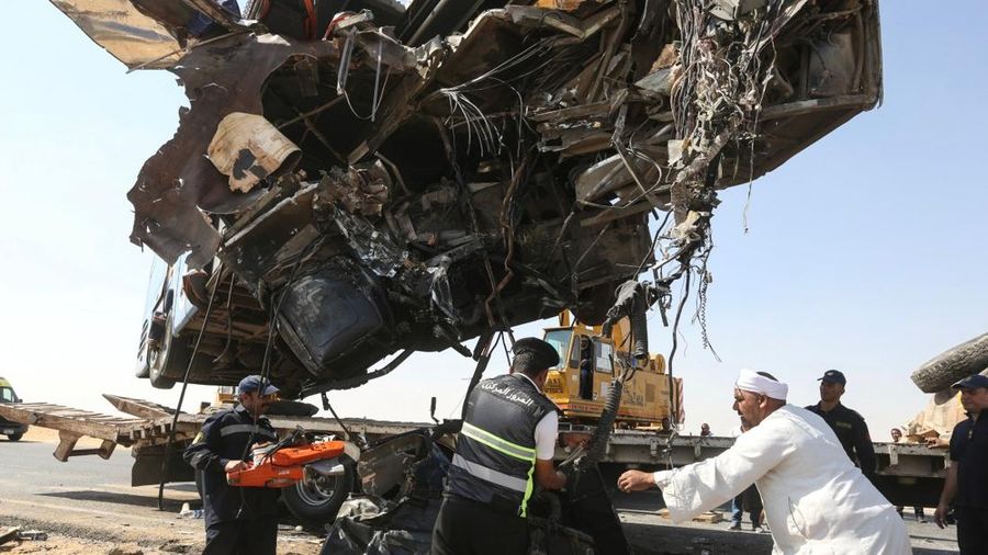 A crane lifts the wreckage of a tour bus following a crash on the desert highway in Giza on October 20, 2026. A large truck crashed into a tour bus west of the Egyptian capital on October 20, killing 13 people and injuring 34, state media reported. (
