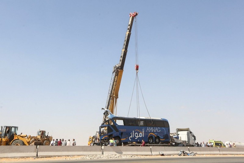 A crane lifts the wreckage of a tour bus following a crash on the desert highway in Giza on October 20, 2026. A large truck crashed into a tour bus west of the Egyptian capital on October 20, killing 13 people and injuring 34, state media reported. (Photo by Khaled KAMEL / AFP)