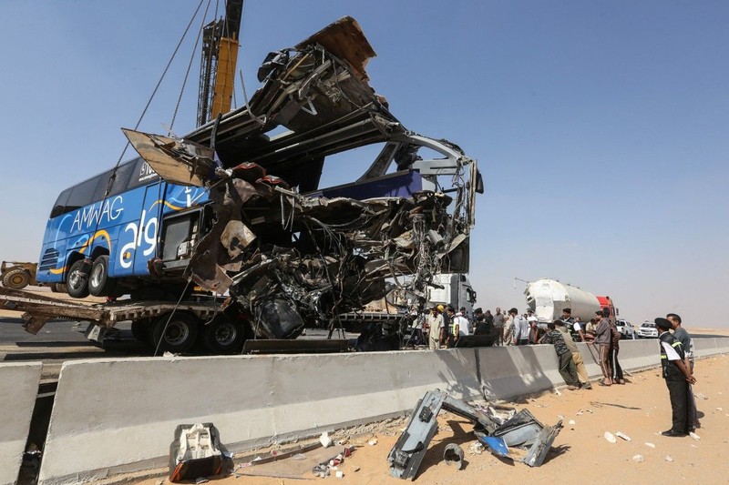 A crane lifts the wreckage of a tour bus following a crash on the desert highway in Giza on October 20, 2026. A large truck crashed into a tour bus west of the Egyptian capital on October 20, killing 13 people and injuring 34, state media reported. (Photo by Khaled KAMEL / AFP)