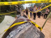 This picture taken on October 19, 2026 shows Indonesian police officers inspecting a large charred metallic fragment, suspected to be rocket debris, at an oil palm plantation in East Kotawaringin Regency, in Indonesia's Central Kalimantan province. I